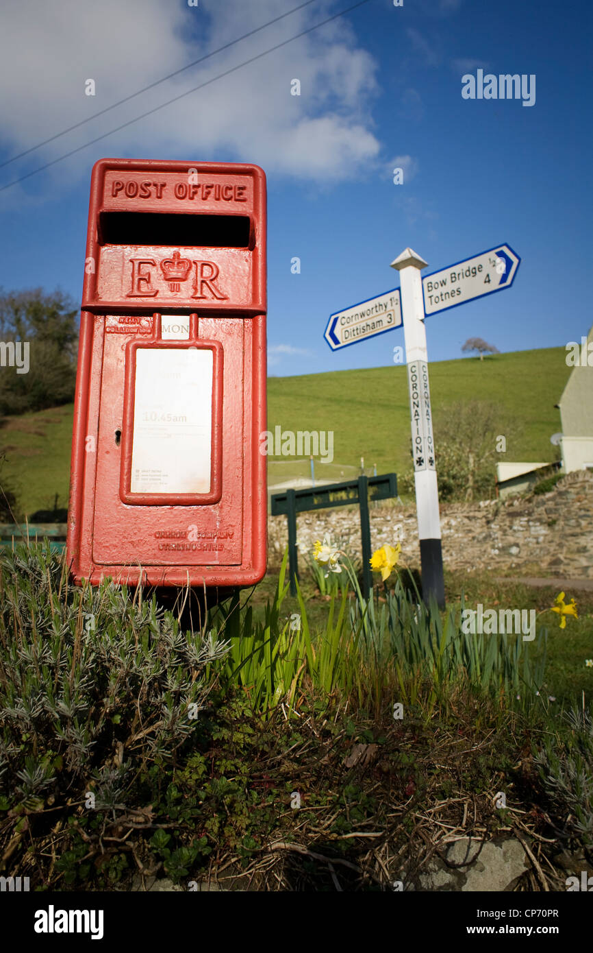 Traditional red postbox in rural scene and sign post, Devon, England. Stock Photo