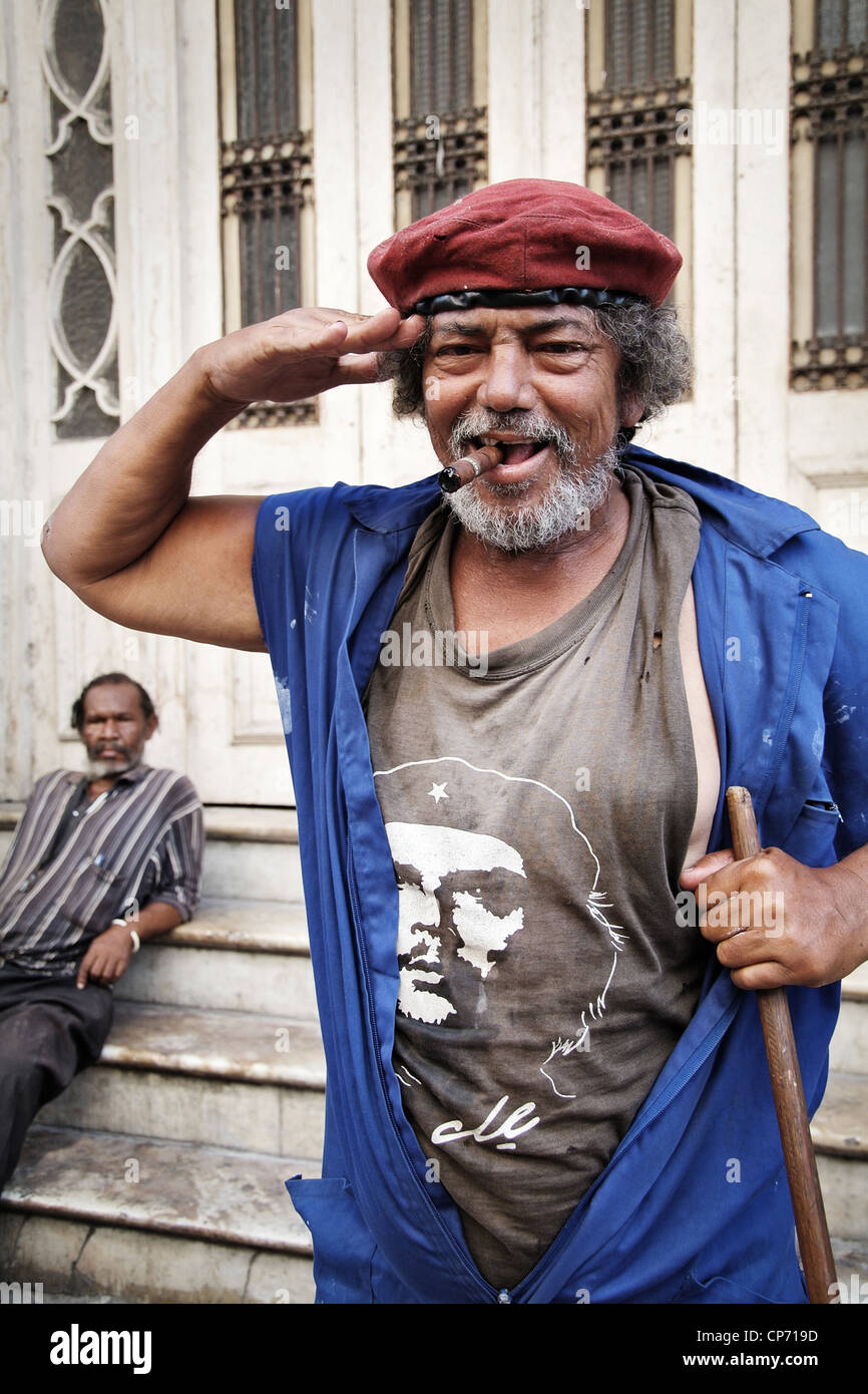 A saluting street cleaner wearing a Che-Shirt and a red beret, smoking a cigar, Havana, Cuba Stock Photo