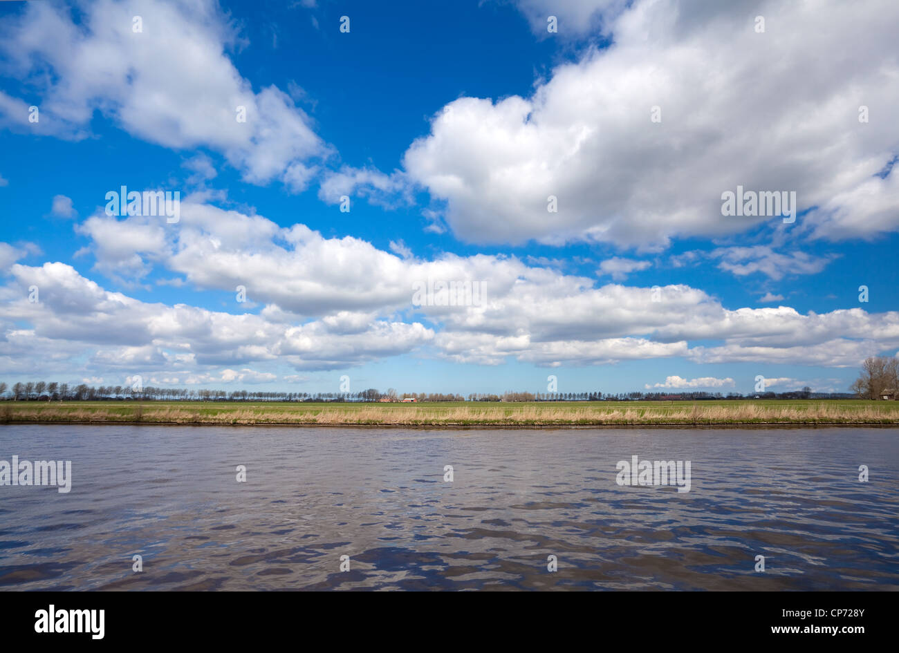 lines of land, water and blue sky with blue puffy clouds Stock Photo