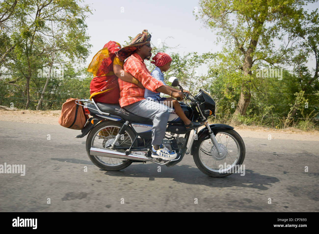 A family of three riding along a highway in Uttar Pradesh, India. Stock Photo