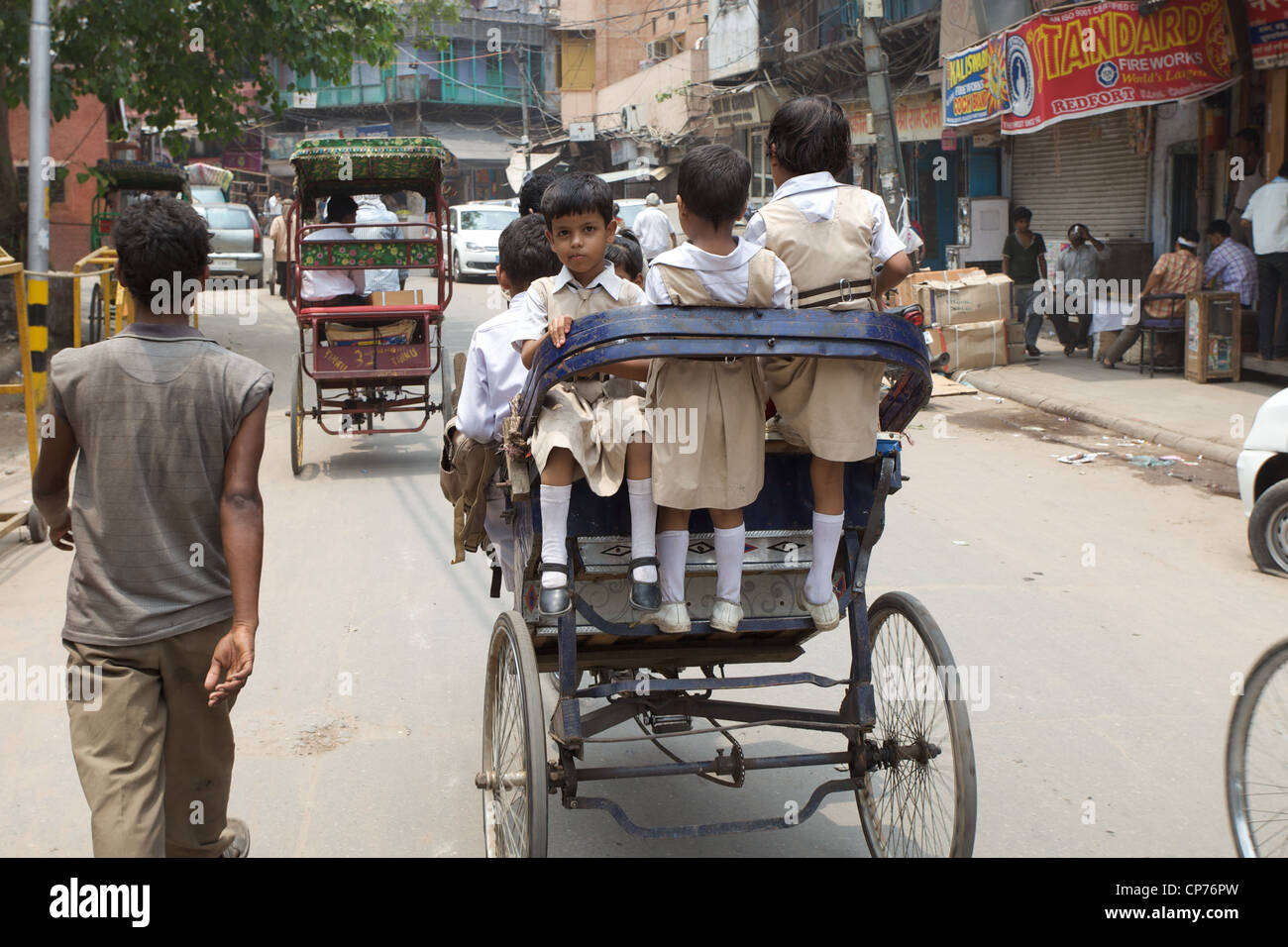 A young girl, half smiling at camera, rides to school on a rickshaw, daily life Old Delhi, India. Stock Photo