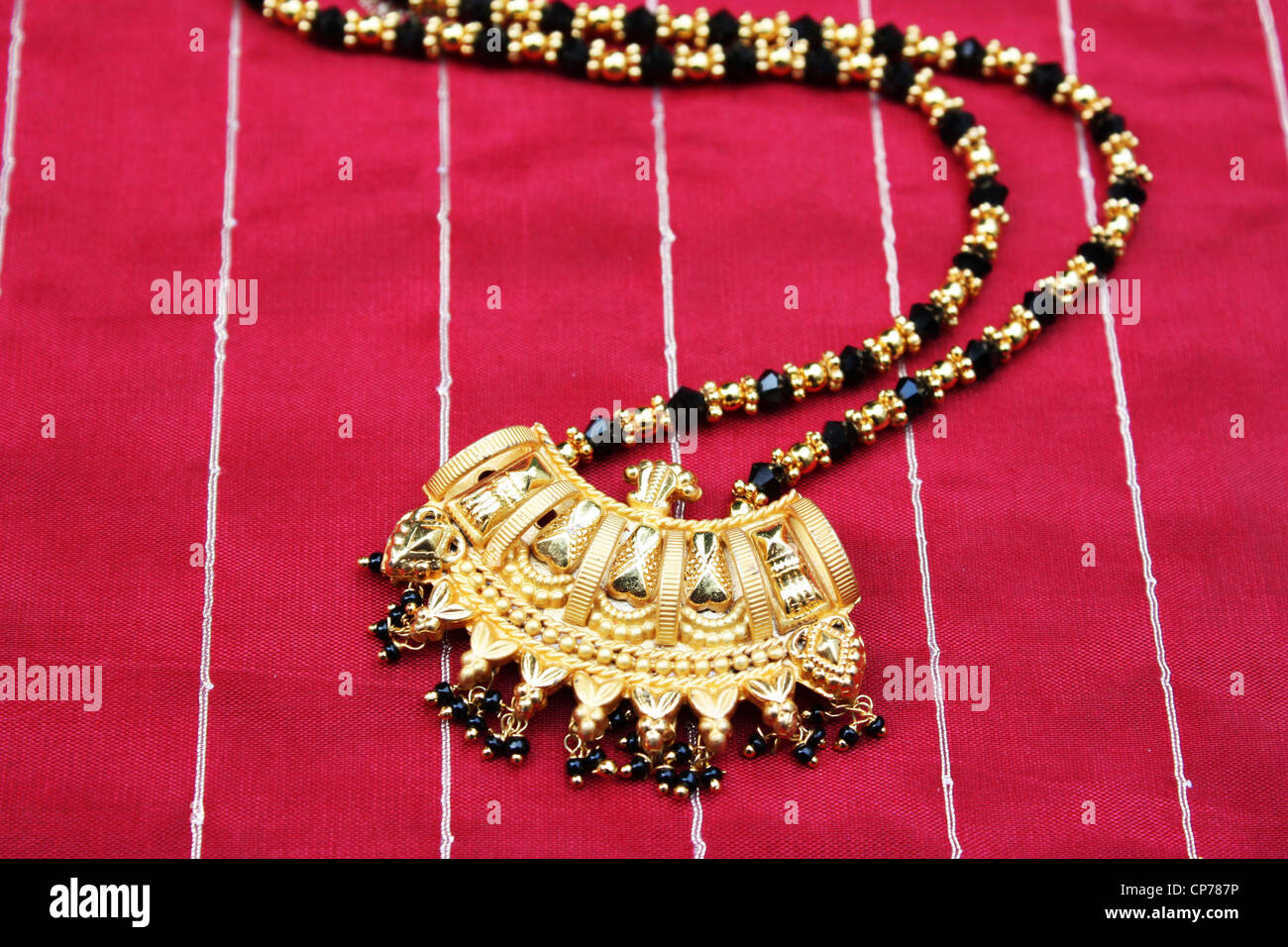 Traditional Indian gold jewelry on red silk fabric Stock Photo