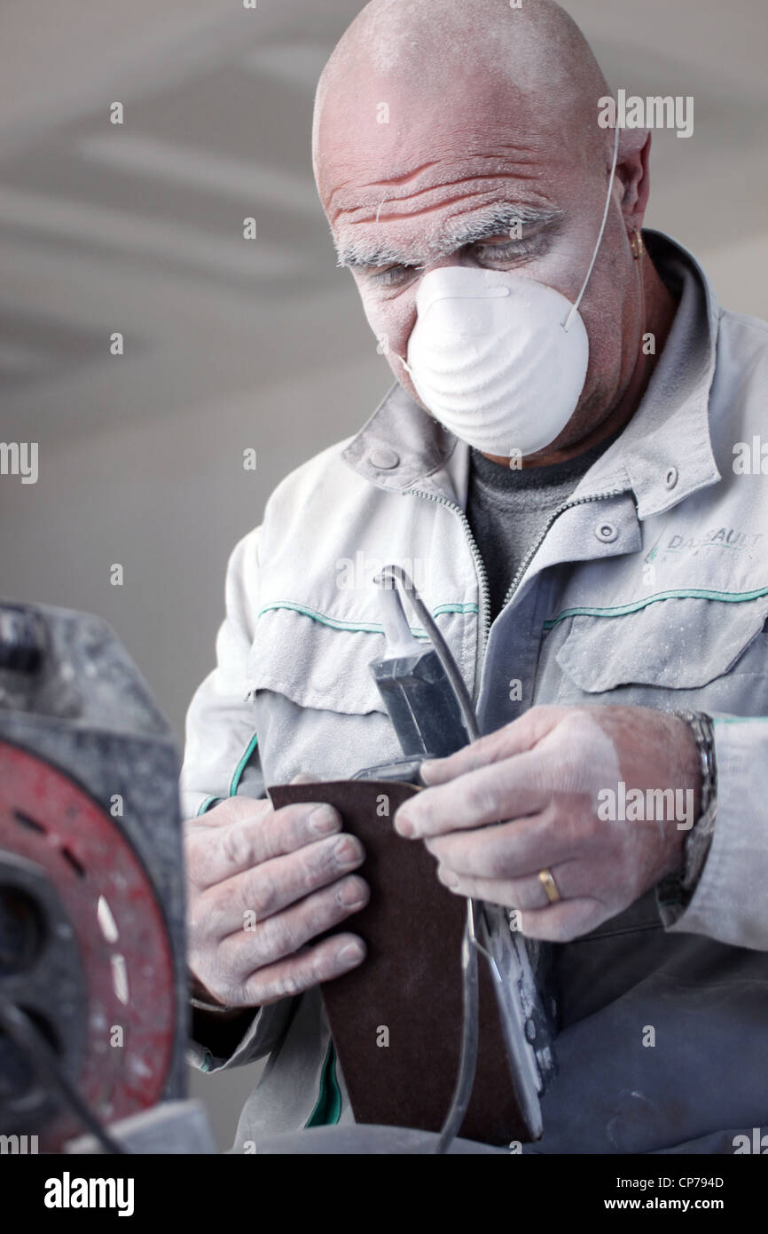 Man wearing mask whilst sanding Stock Photo Alamy