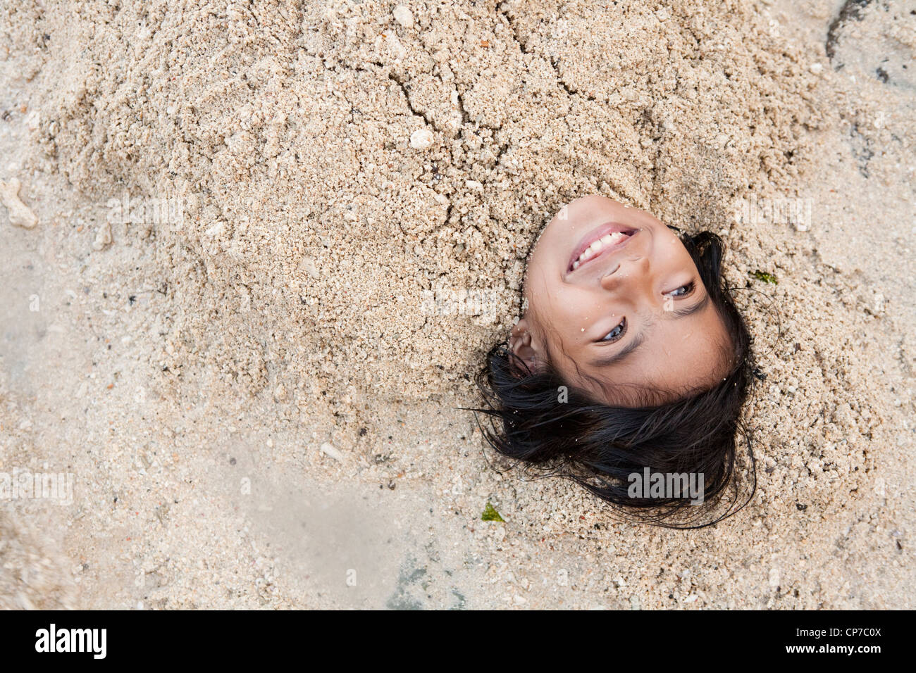 Filipino girl being buried in the sand at Blue Reef Mactan Island Resort. Lapu-Lapu City, Metro Cebu, Mactan Island Philippines Stock Photo