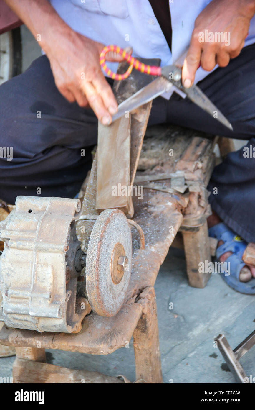 Man sharpens knives and scissors on the street of Hue, Vietnam Stock Photo