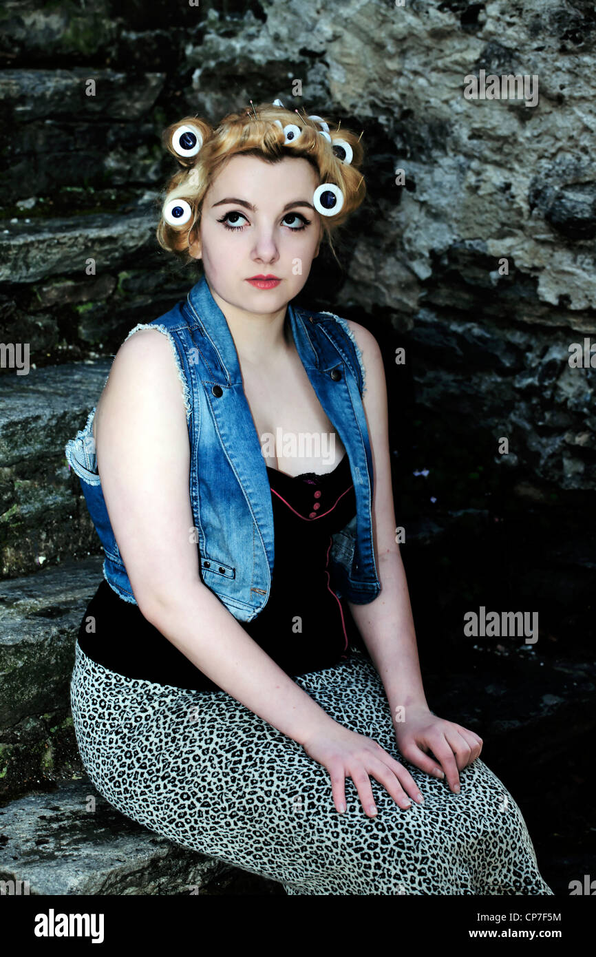 young woman with curlers sitting on stone steps Stock Photo