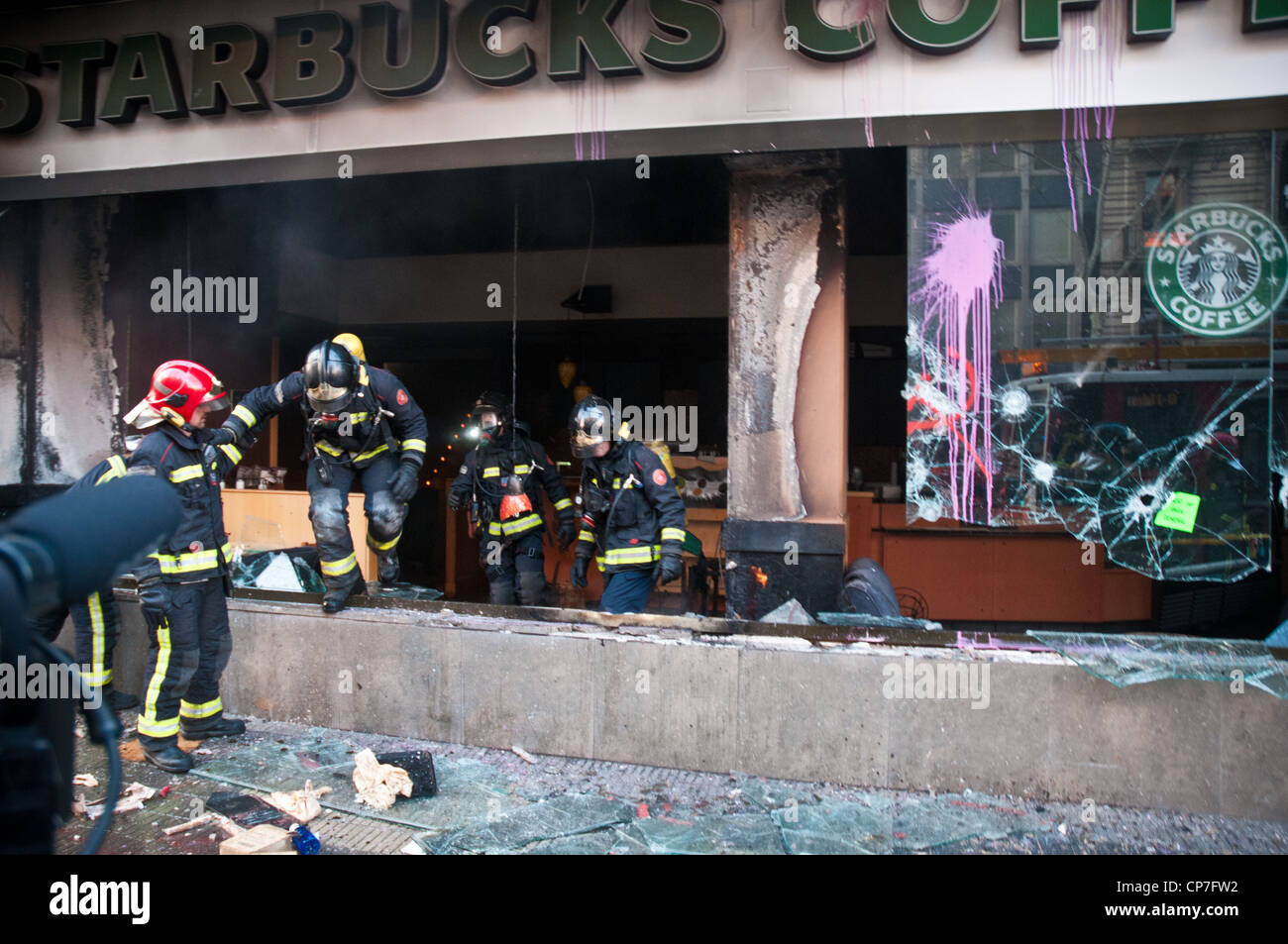 Firemen climb out of a burned Starbucks after protesters set it on fire during the general strike in Barcelona. Stock Photo