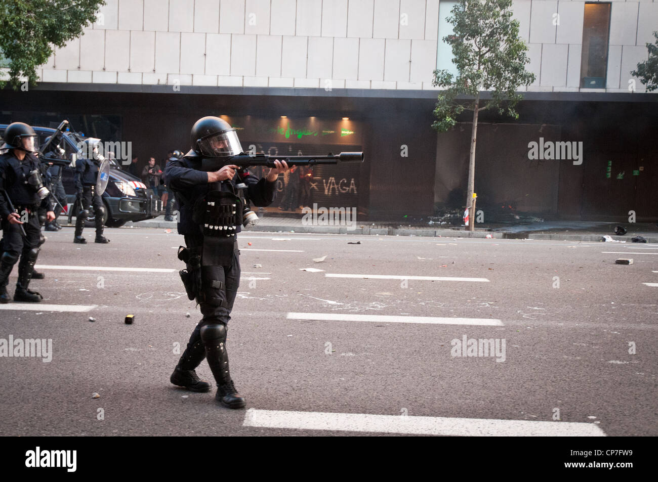 A riot police officer fires rubber bullets at protesters during the general strike in Barcelona