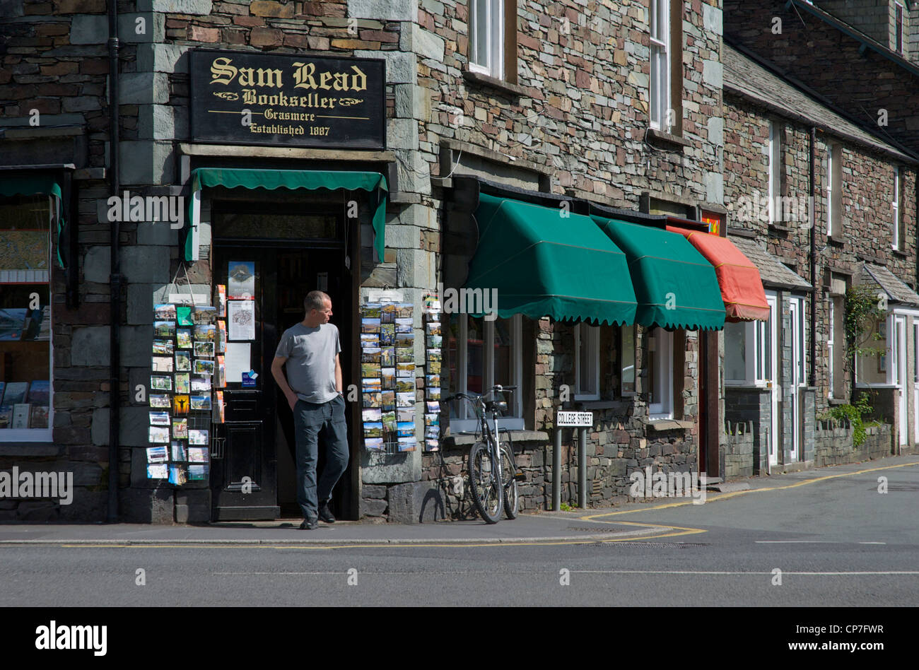 Man coming out of bookshop in the village of Grasmere, Lake District National Park, Cumbria, England UK Stock Photo