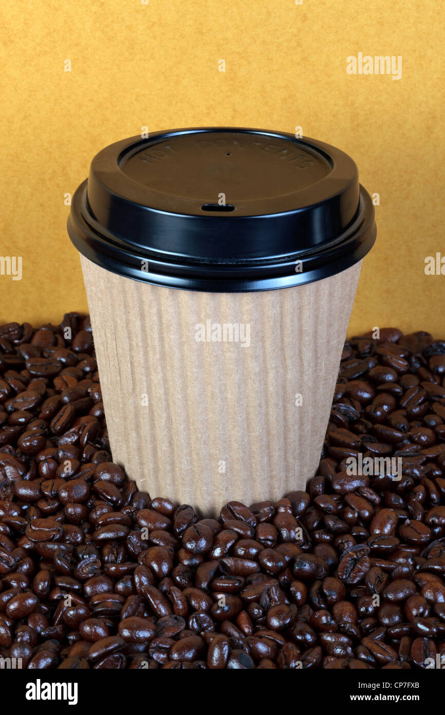 Photo of a takeaway paper coffee cup with lid on a mixture of arabica and robusta beans. Stock Photo