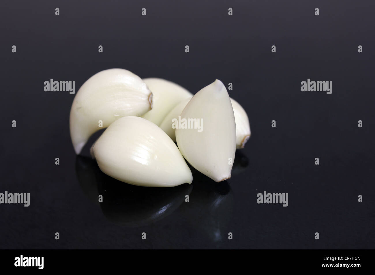 Garlic (Allium sativum) cloves separated from the bulb in black background Stock Photo