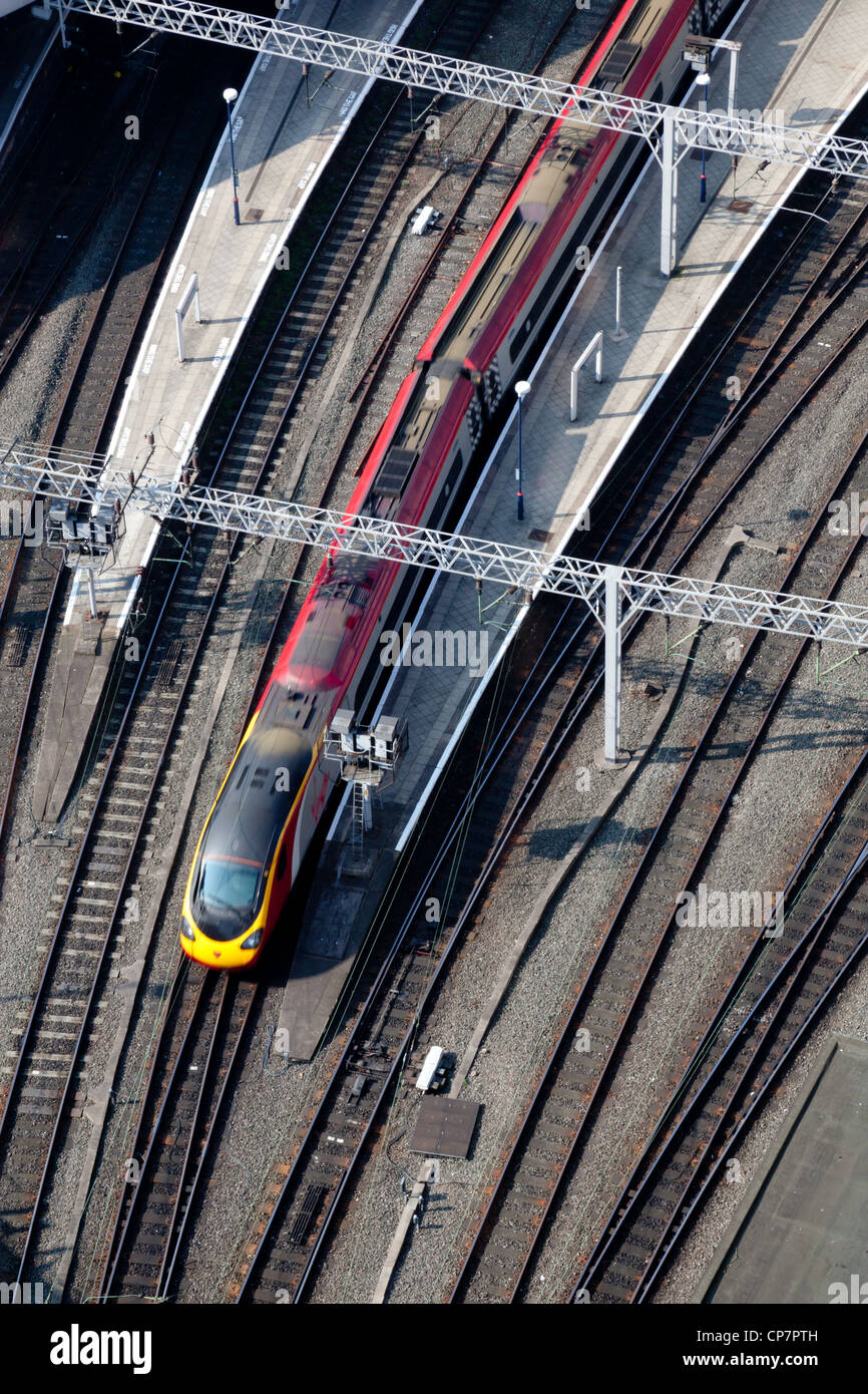 Bird's eye view of a train approaching a station, sidelit in the morning light. Stock Photo