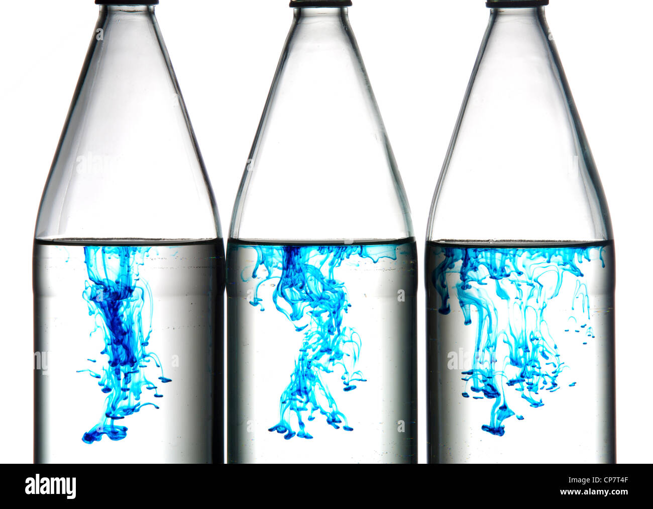 Blue food coloring makes interesting designs in bottles of water. Stock Photo