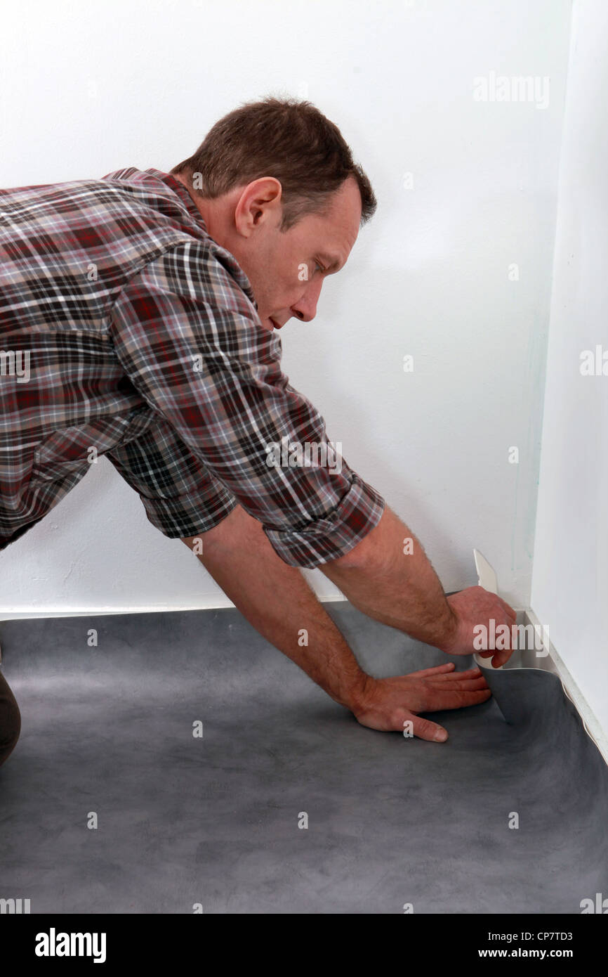 Man pushing lino flooring to fit into a corner Stock Photo Alamy