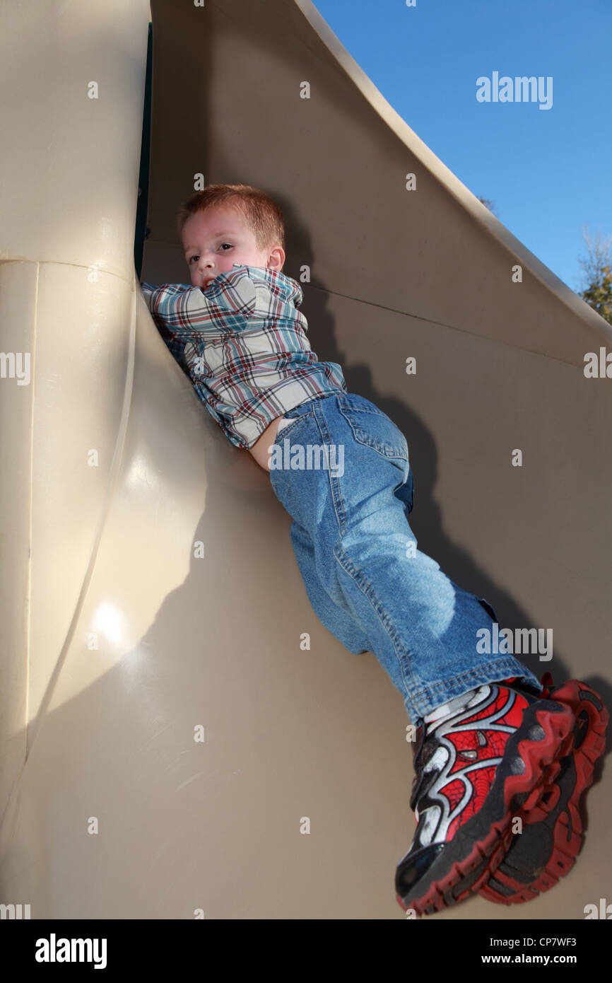 A young boy is playing on a slide Stock Photo