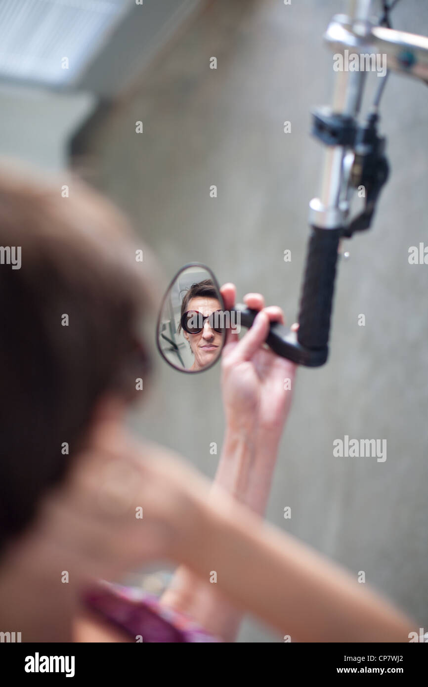 Woman checking herself in the bicycle mirror. Stock Photo