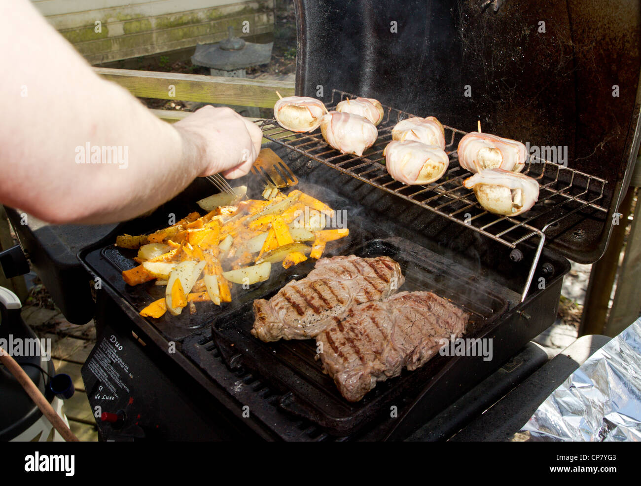 man grilling mushrooms,beacon,beef and potato Stock Photo - Alamy