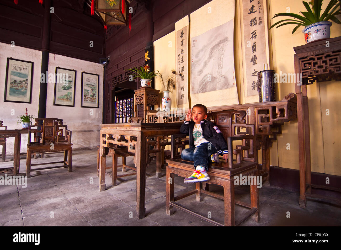 Chinese boy sitting on a beautiful wooden chair in a old house - Zhouzhuang watertown near Shanghai - China Stock Photo