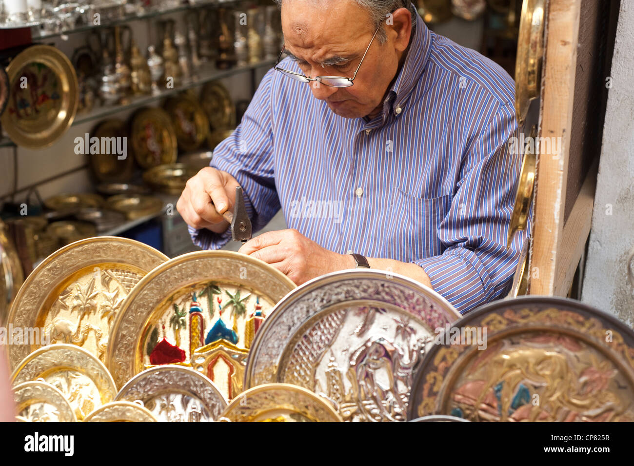 Tunis, Tunisia - Craftsman punches out pattern on decorative brass plate  at souq market in the UNESCO World Heritage. Stock Photo