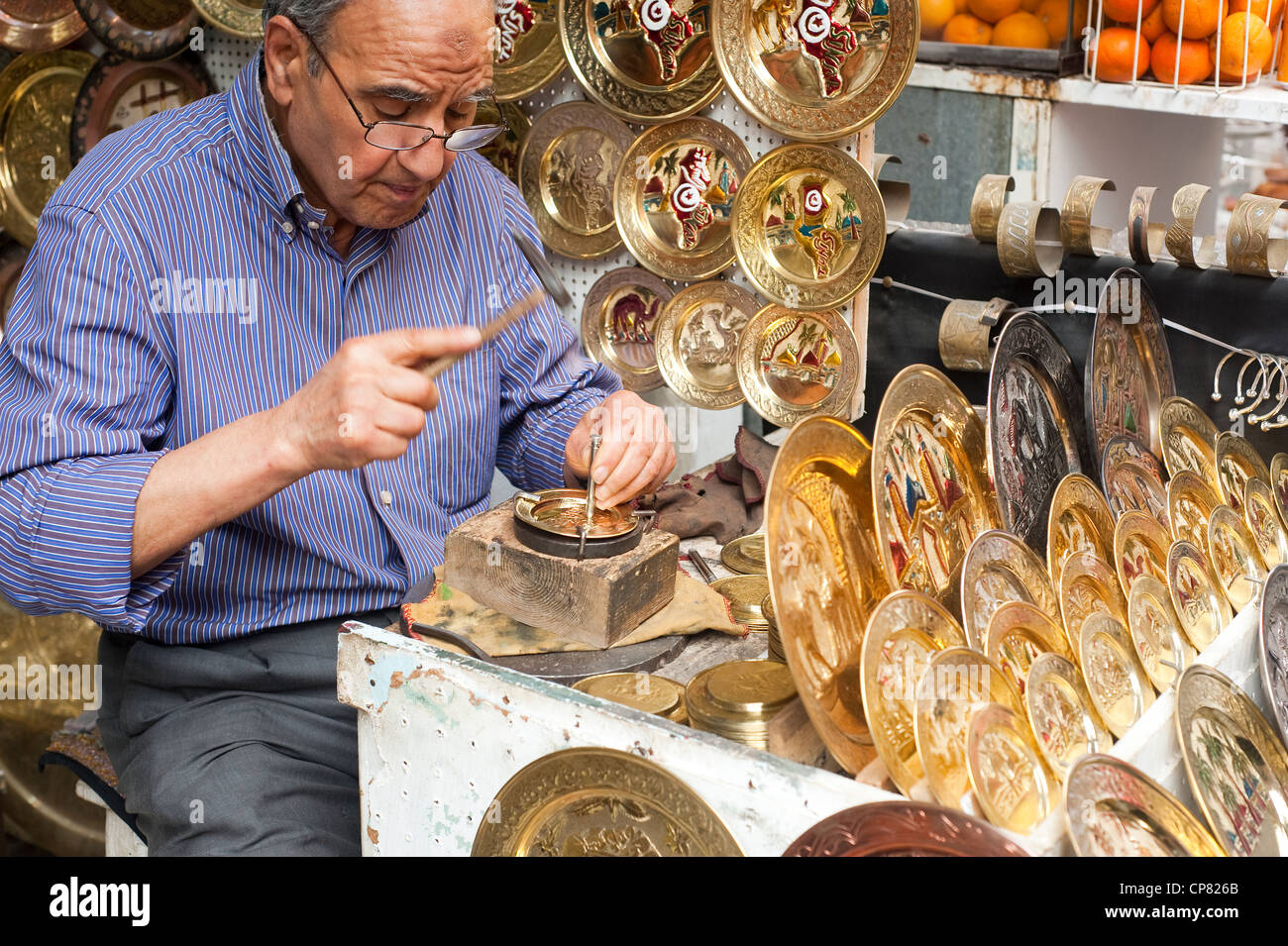 Tunis, Tunisia - Craftsman punches out pattern on decorative brass plate  at souq market in the UNESCO World Heritage. Stock Photo