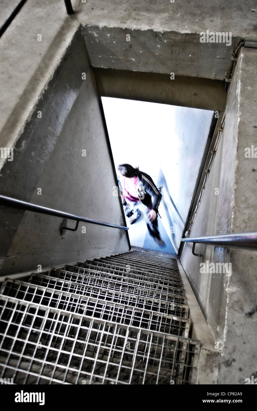 A staircase leads down into a cellar. Below the silhouette of a man is shown. Stock Photo