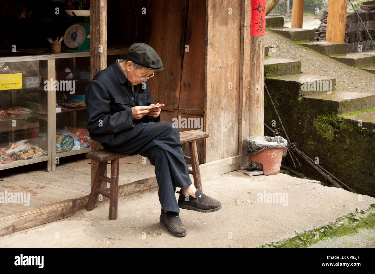 old man reading sitting on a bench, Huangluo Stock Photo - Alamy