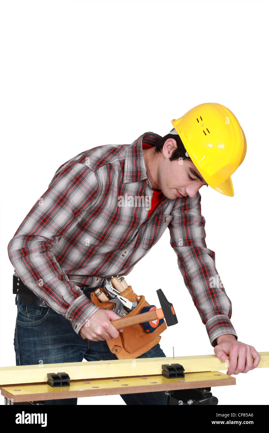young carpenter hammering down nail in plank Stock Photo Alamy