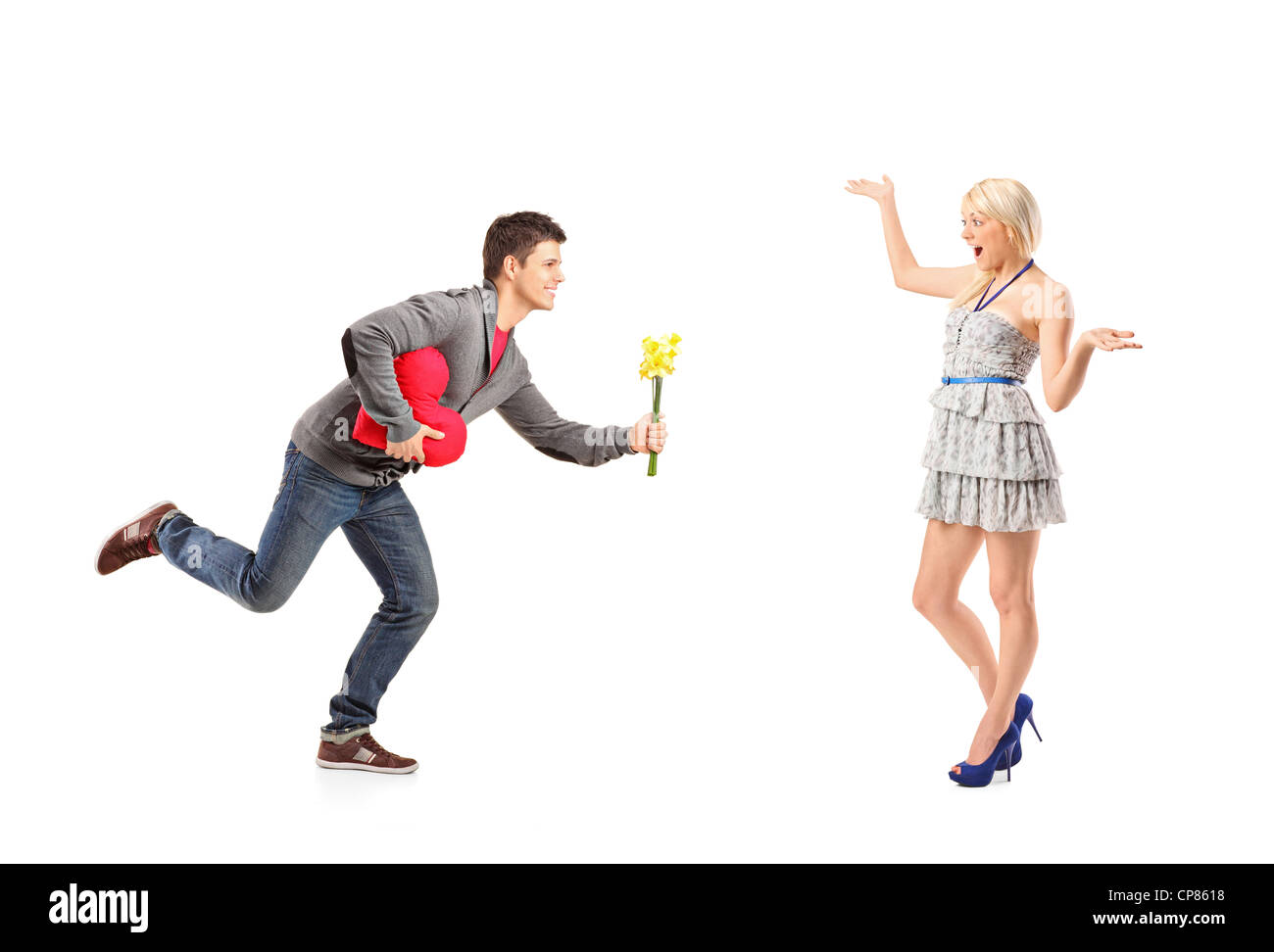 A boyfriend in love running with flowers and heart shape object towards his excited girlfriend isolated on white background Stock Photo