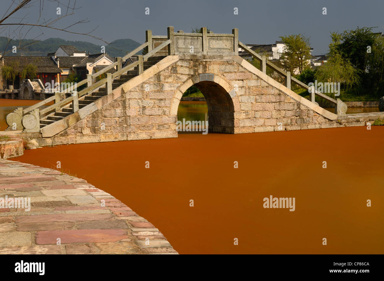 Stone bridge with bright red algae bloom scum on Longxi river in Chengkan village Huangshan Peoples Republic of China Stock Photo