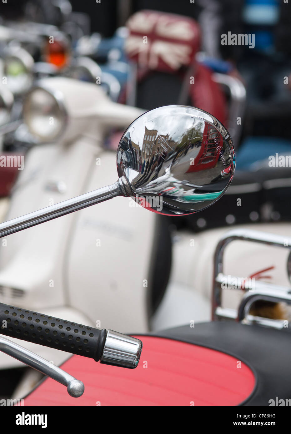 Chrome wing mirror reflects a Cambridge scene at Scooter club rally in Cambridge, England. Stock Photo