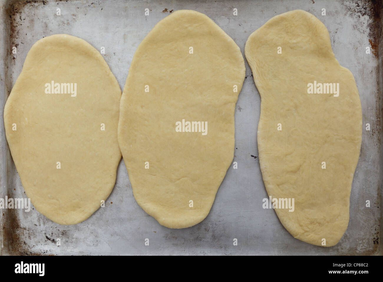Homemade Indian naan bread on an old baking tray ready to go in the oven Stock Photo