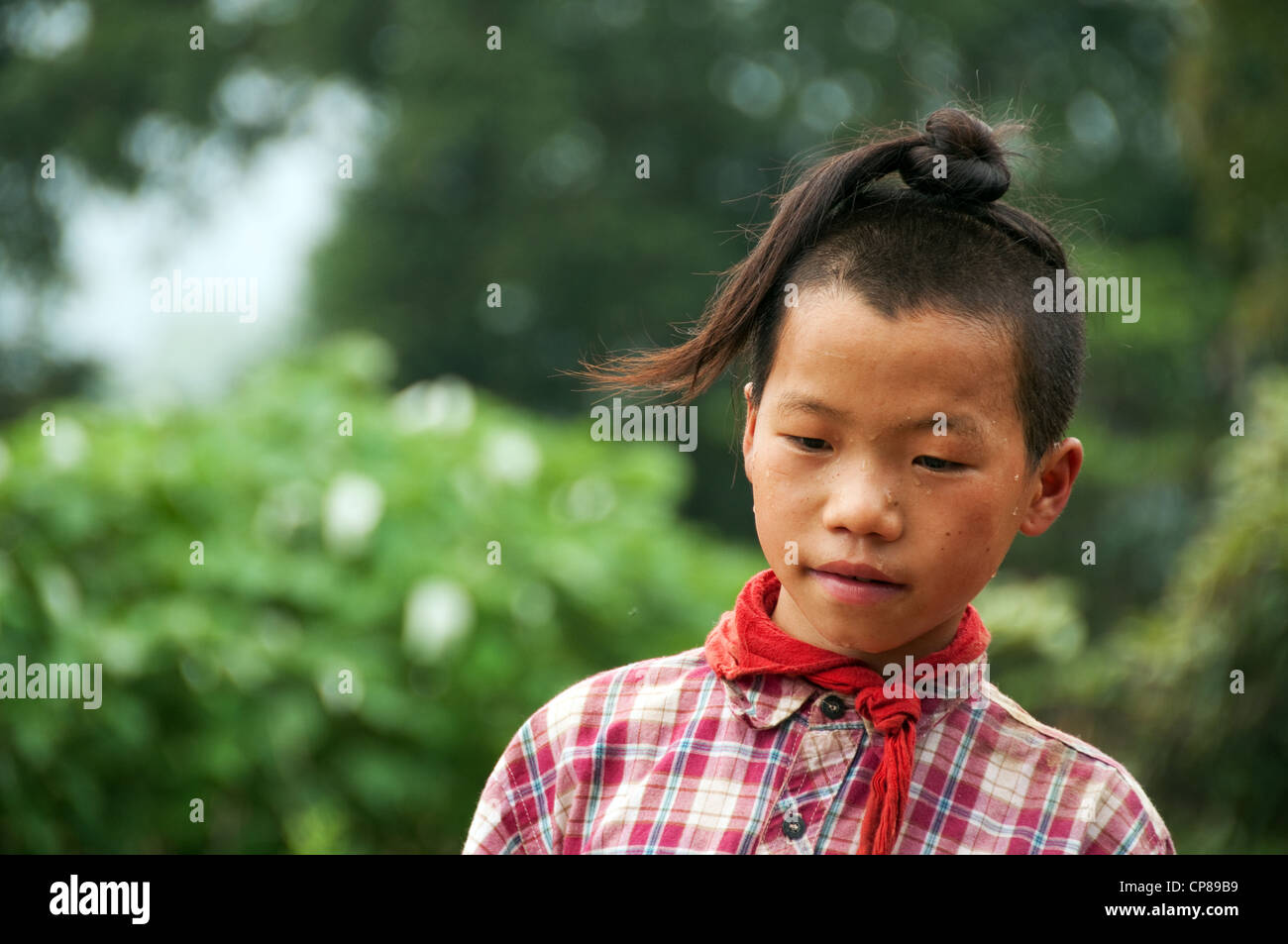 Sweating young Basha Miao (Gun Men) boy with traditional hairstyle and red neckerchief, Southern China Stock Photo