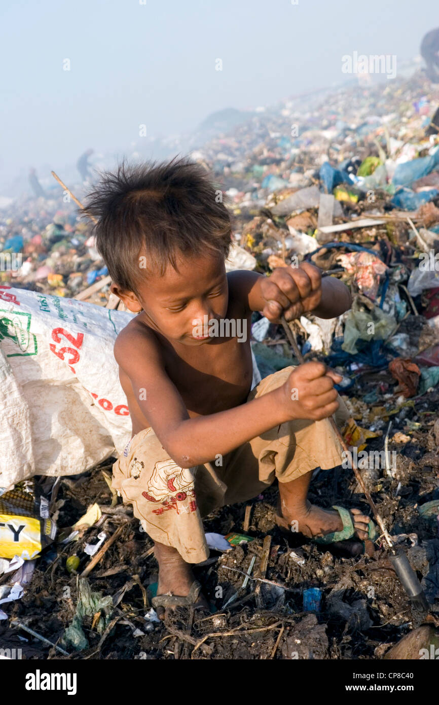 A young boy child laborer is using a gaff to collect soft clear plastic ...