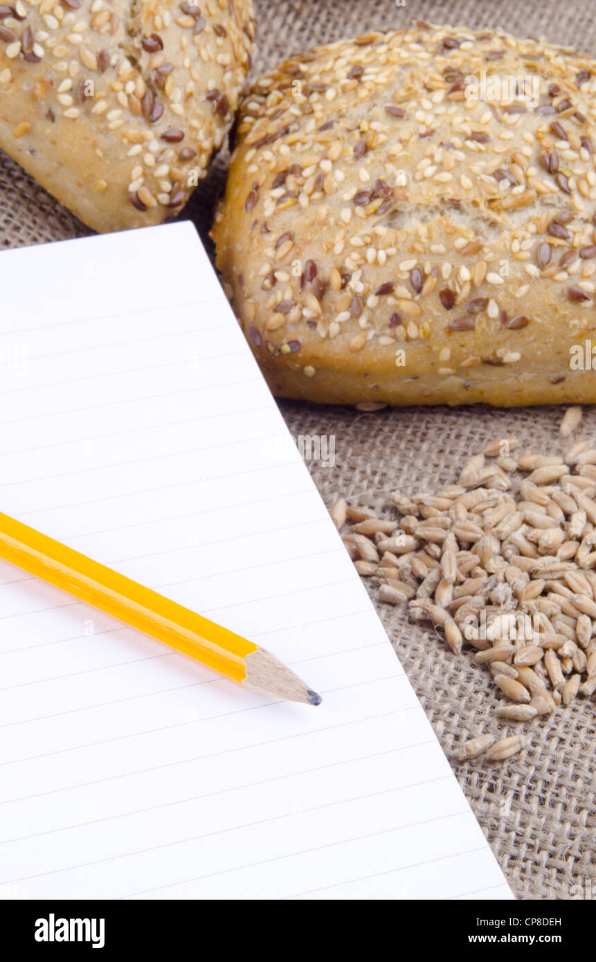 multigrain roll and a booklet for notes with pencil Stock Photo