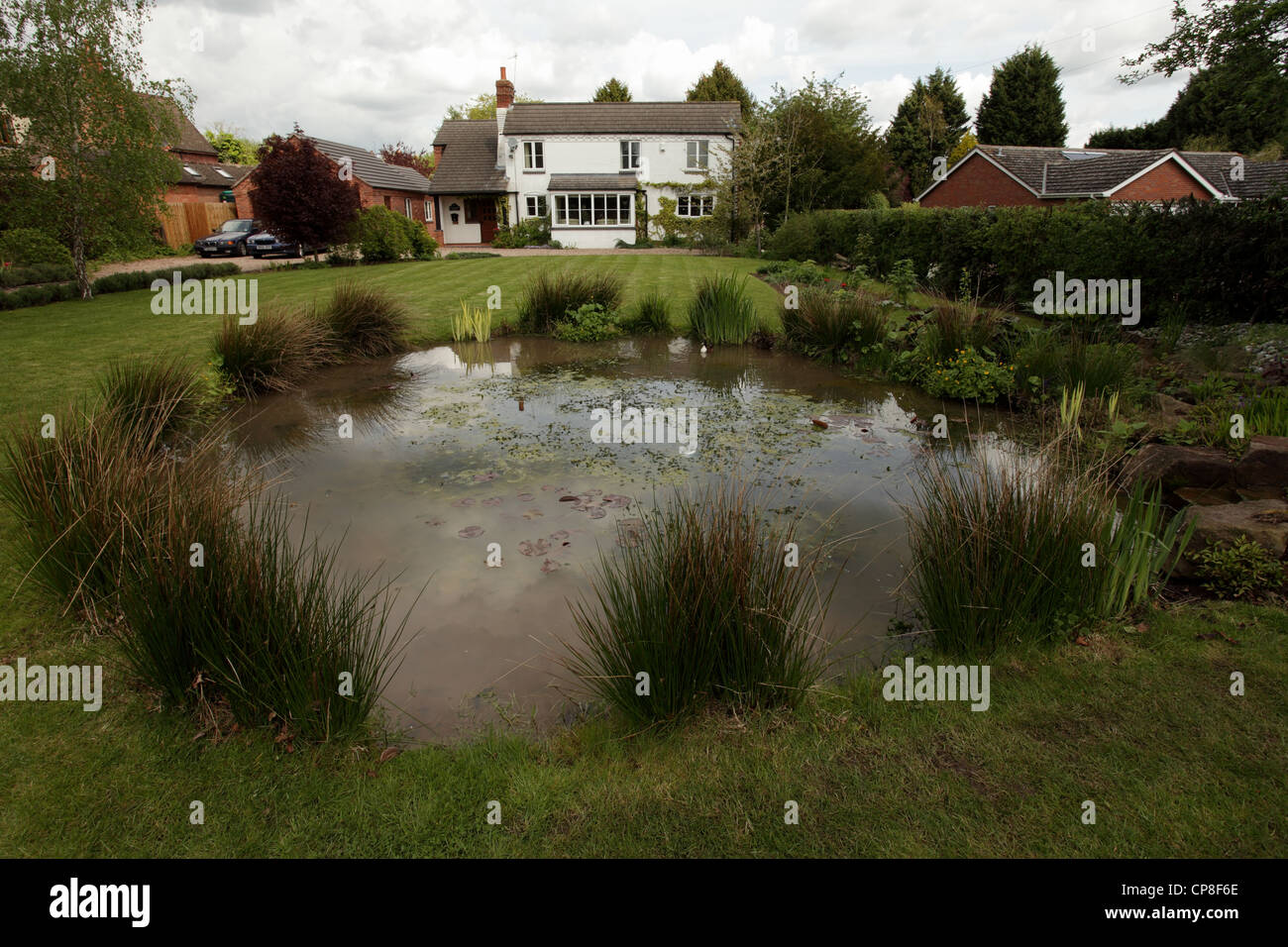 Village house with a pond in the front garden, England UK Stock Photo