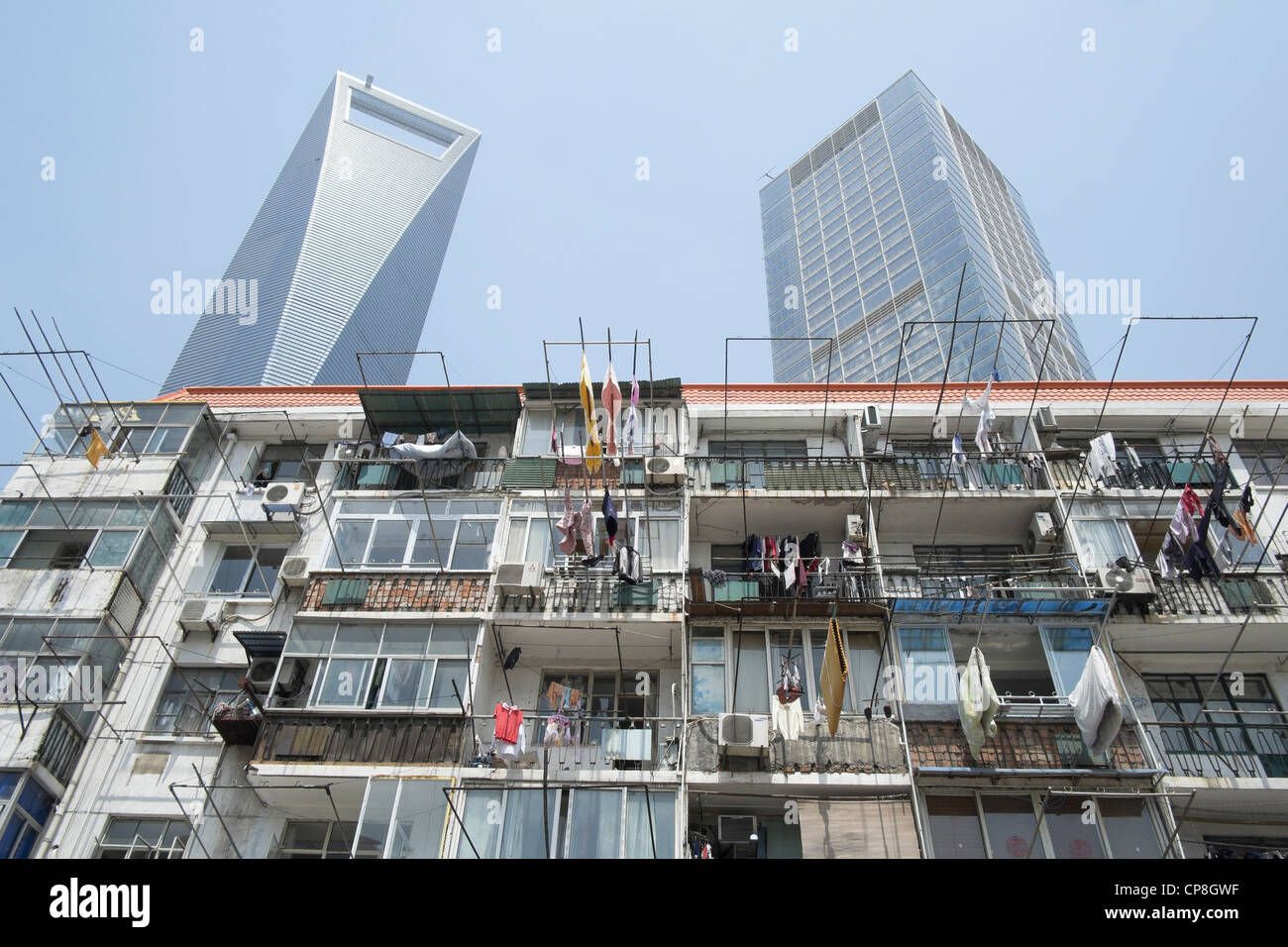 Contrast between old apartment buildingg with modern skyscrapers to rear in Lujiazui financial district in Shanghai China Stock Photo