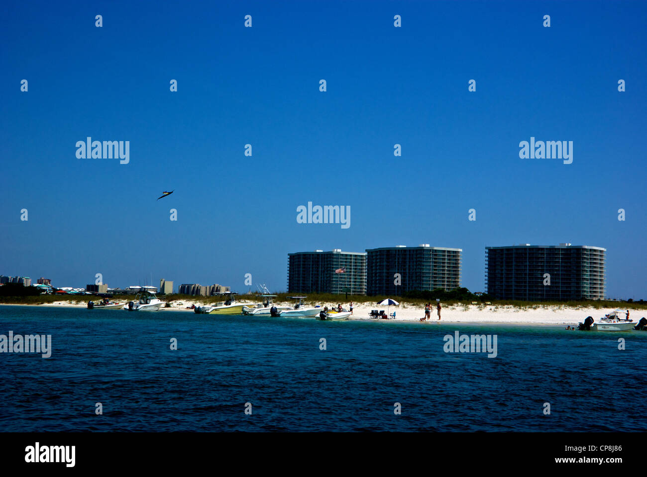 Recreational boaters sunbathers kite flier white sandy beach key Orange Beach Gulf Shores condominium apartment towers Stock Photo