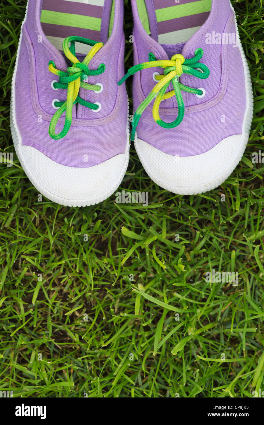 Colourful childs plimsolls on a grass lawn Stock Photo