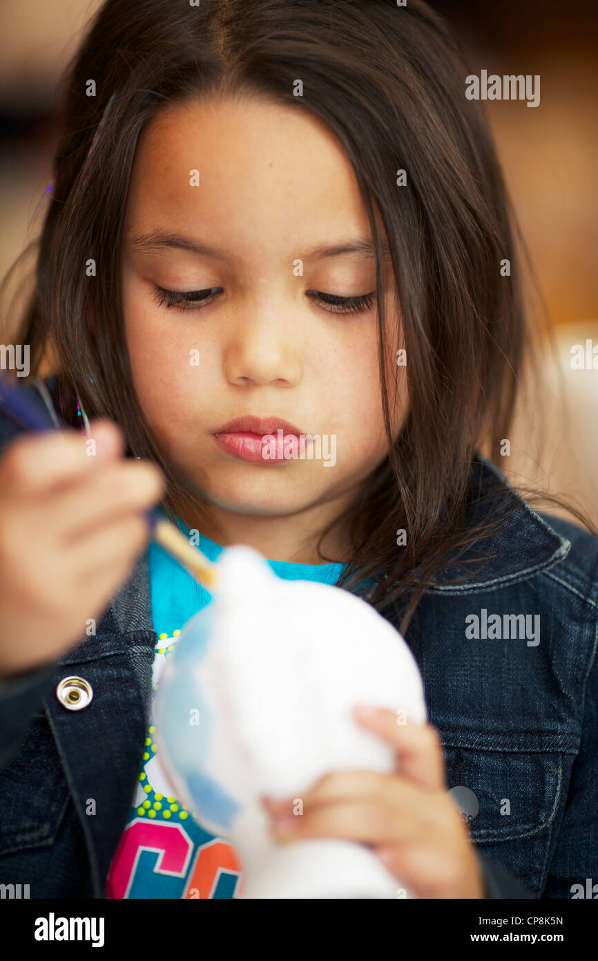 Seven year old girl painting ceramic soccer ball Stock Photo Alamy