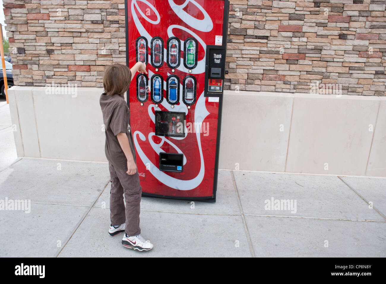 Boy making a selection in front of a soda pop vending machine. Stock Photo