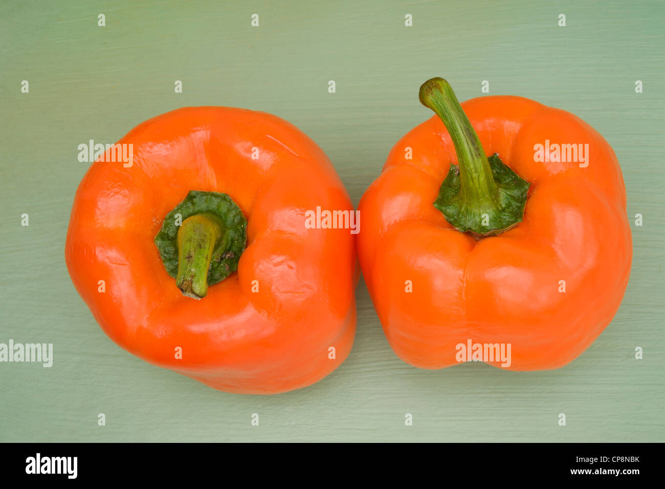 Orange bell peppers on a green background Stock Photo - Alamy