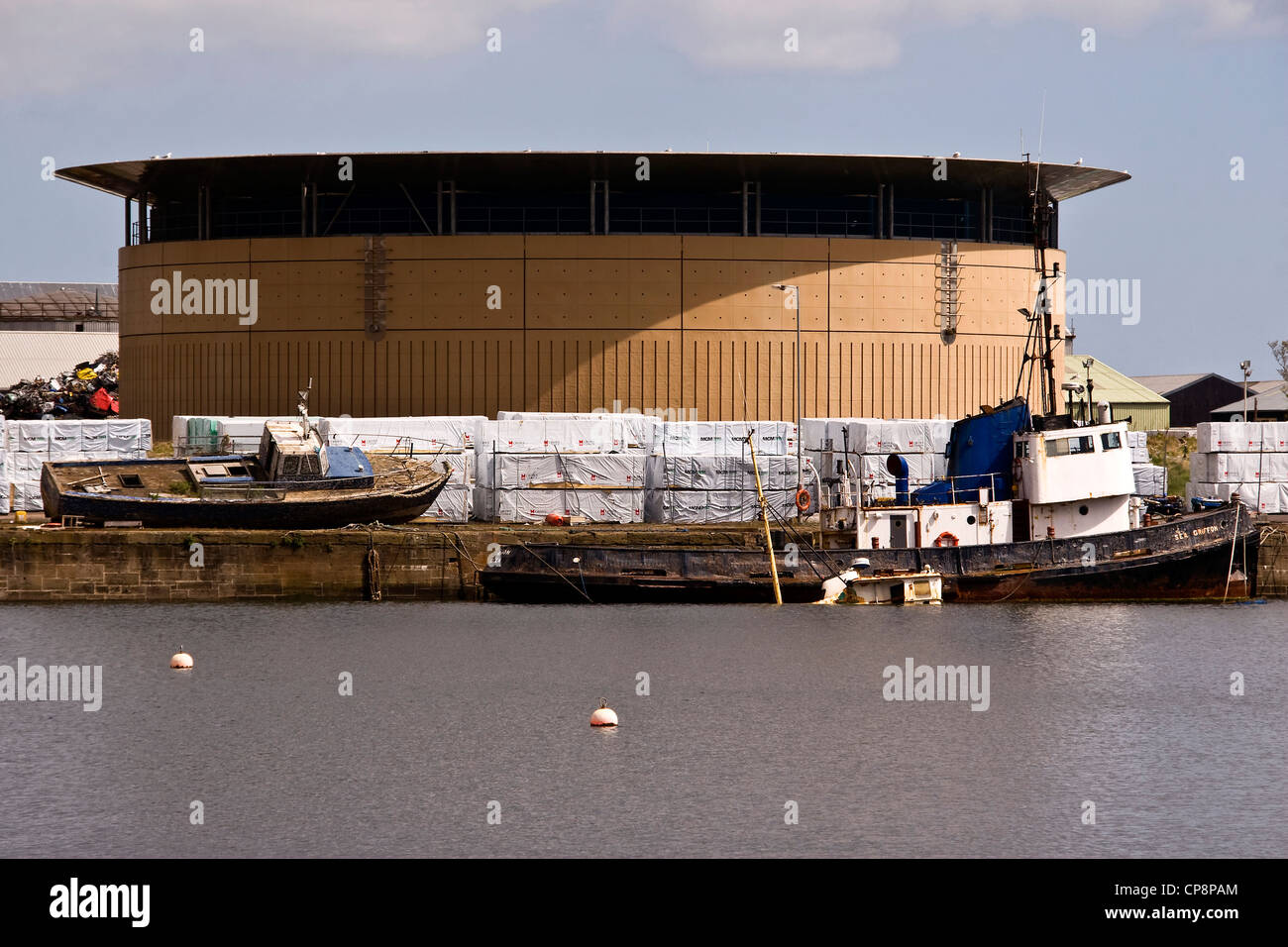 Abandoned and decaying boats beside a gas tank at Victoria Docks in industrial Dundee,UK Stock