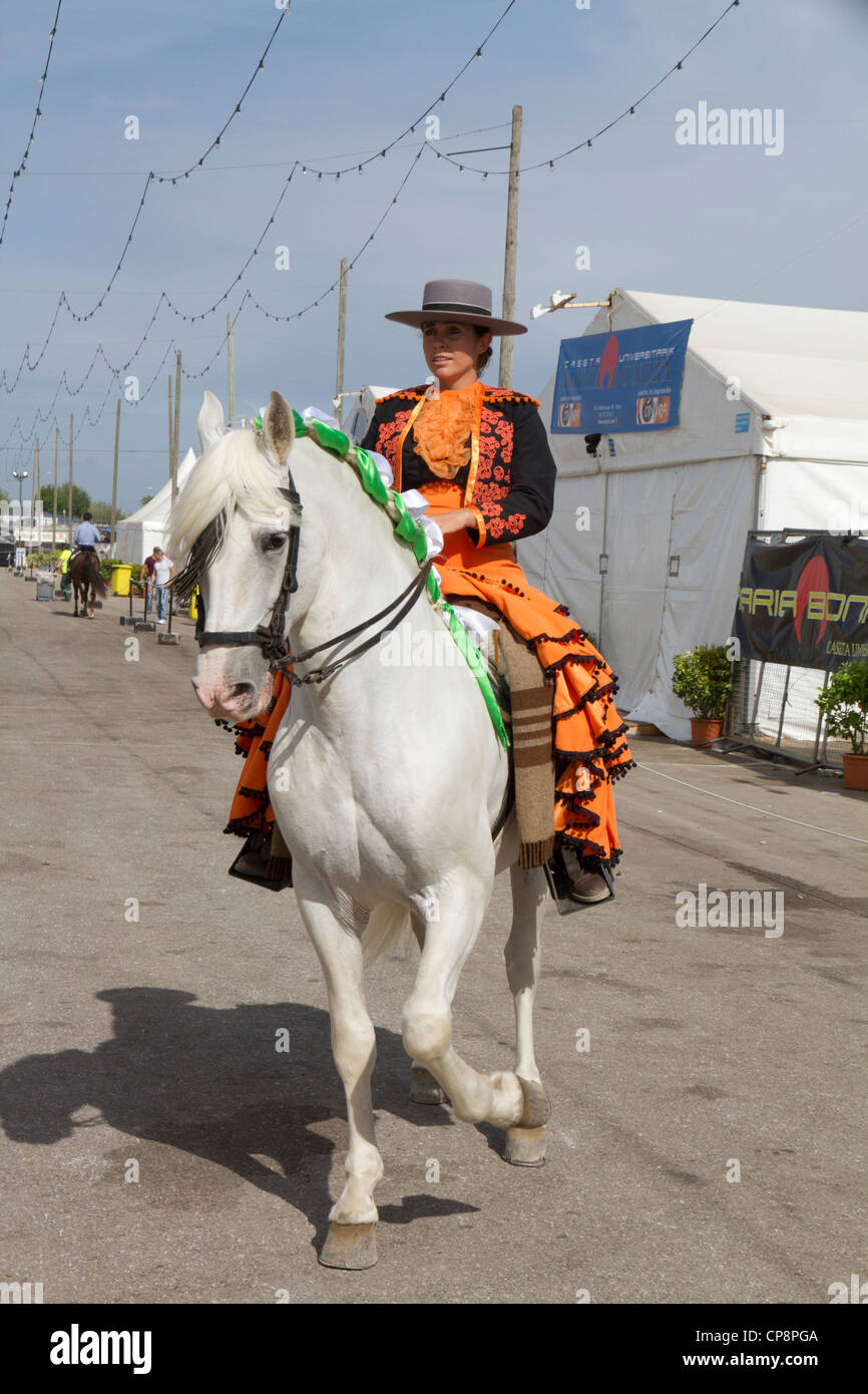 Andalucian woman in traditional dress on white horse at Fira de Abril Fair Spain Stock Photo