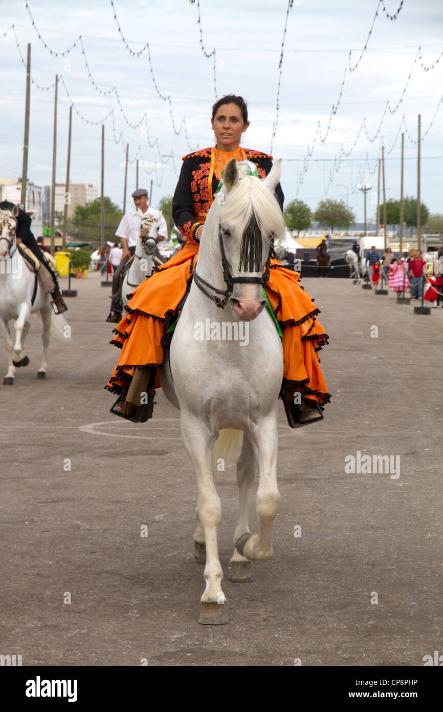 Andalucian woman in traditional dress on white horse at Fira de Abril Fair Spain Stock Photo