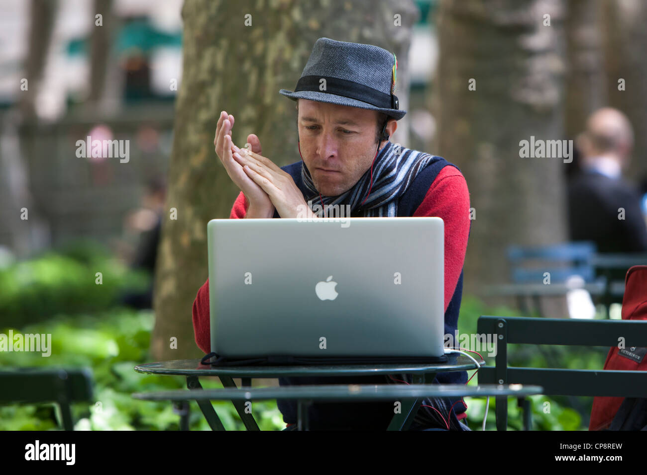 A man works on his Apple Macbook Pro laptop computer in Bryant Park in New York City. Stock Photo
