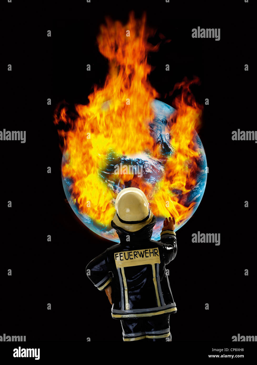 Fireman figurine in front of earth with burning fire, close up Stock Photo