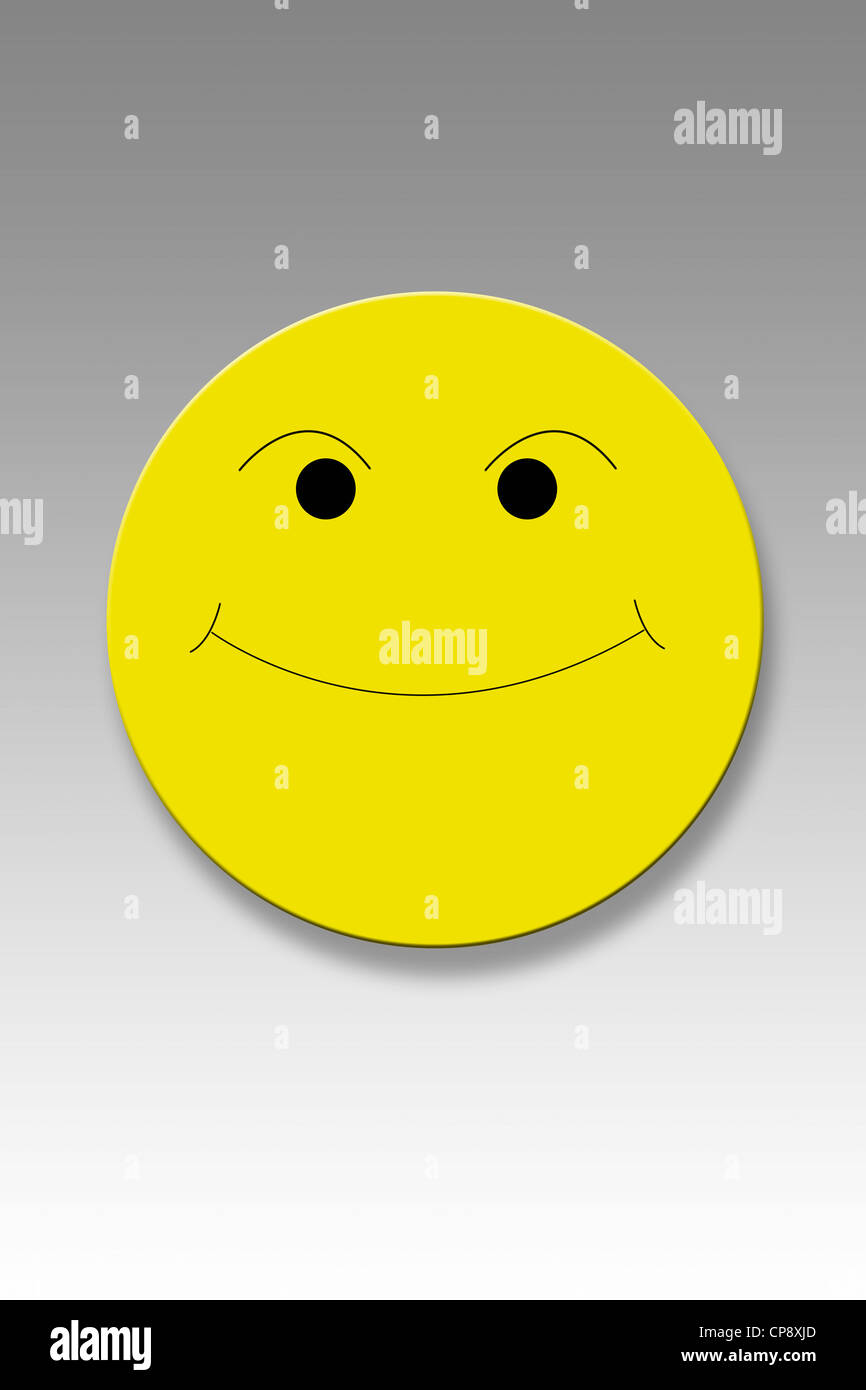 Yellow button with smiley face against grey background Stock Photo