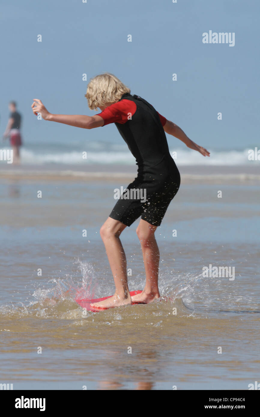 A teenager learning how to surf in shallow waters on the Atlantic coast of South West France Stock Photo