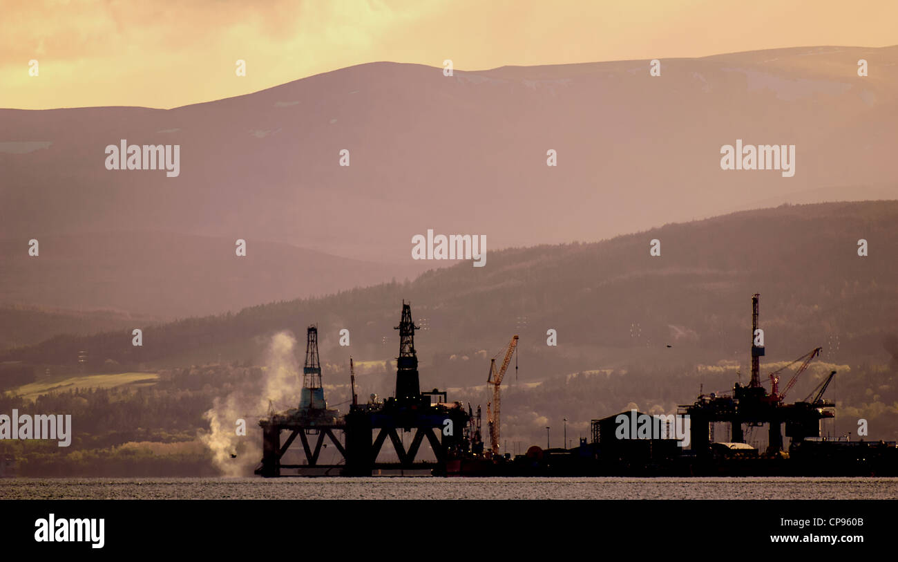 Oil rigs at sunset stand off the village of Invergotdon in the Cromarty Firth, Scotland Stock Photo
