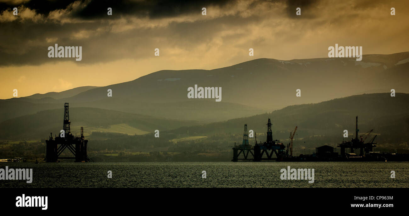 Oil rigs at sunset stand off the village of Invergotdon in the Cromarty Firth, Scotland Stock Photo